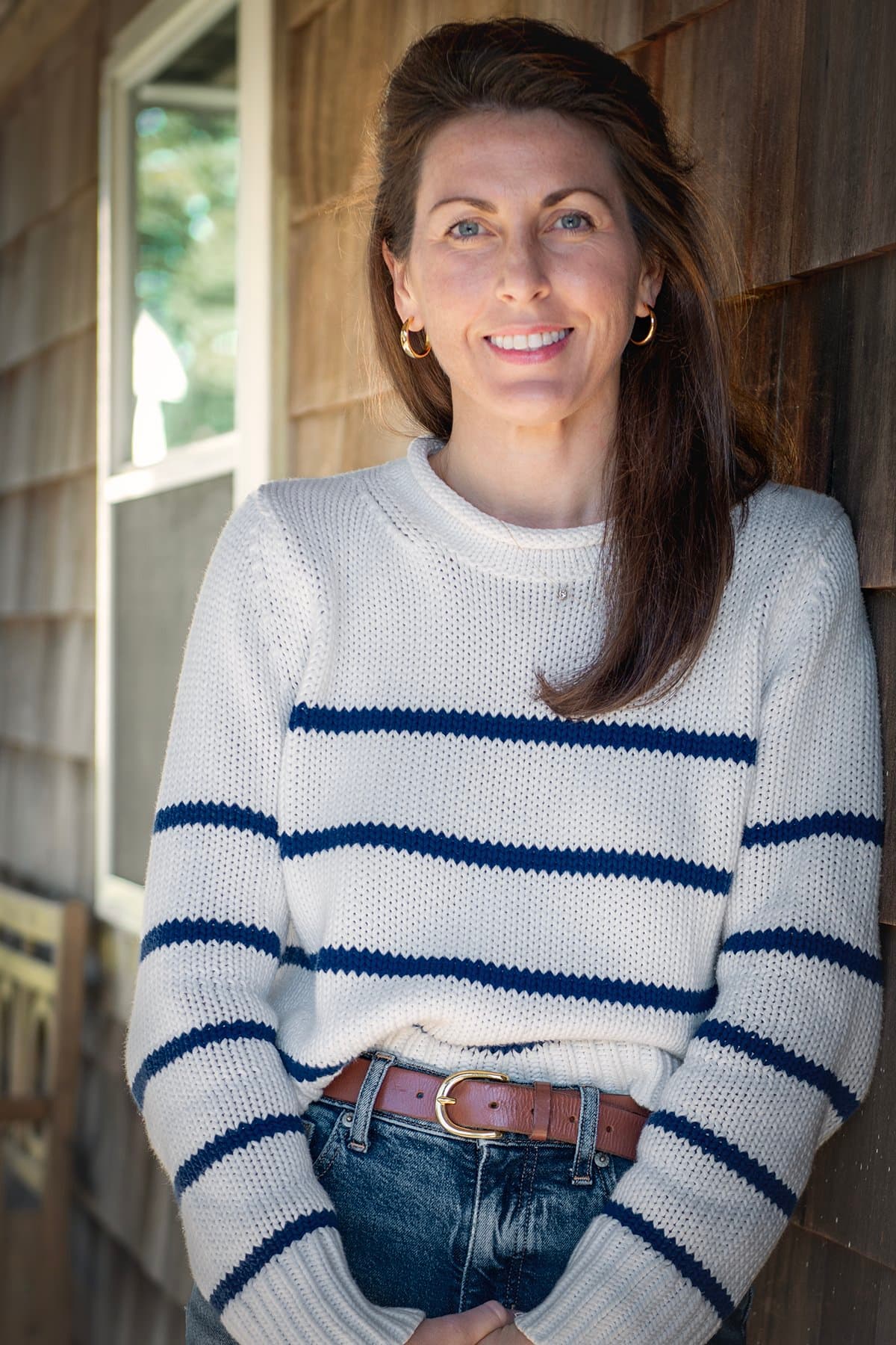 Allie O'Brien leaning against a wooden wall outside