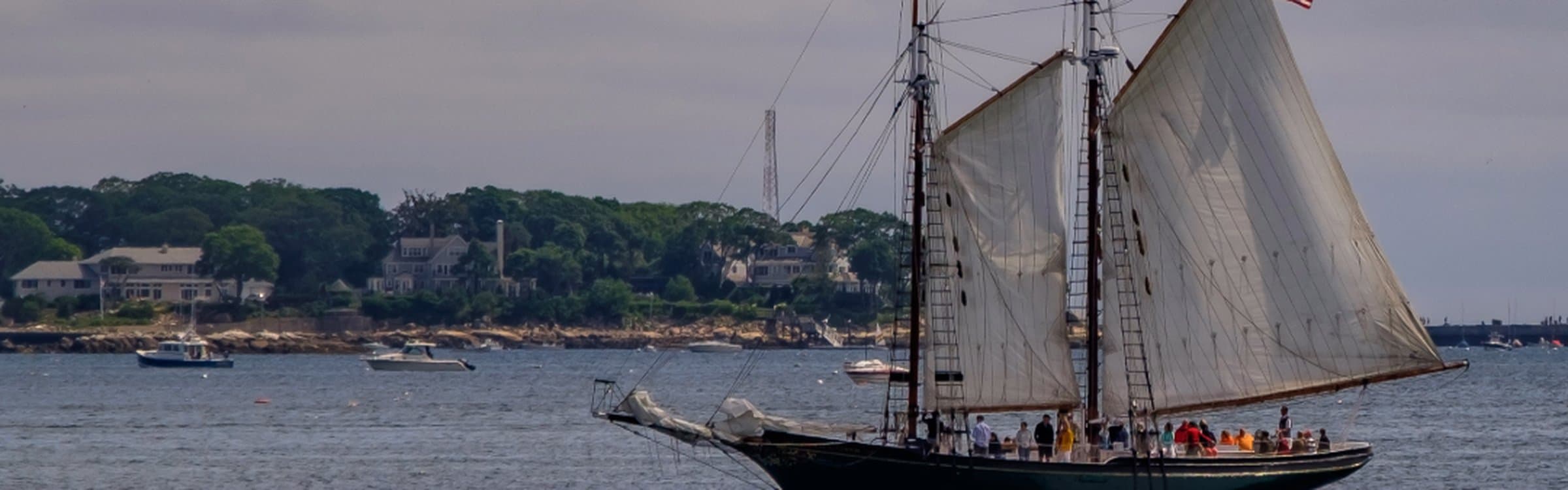 Schooner sailing past the Gloucester coastline on Cape Ann