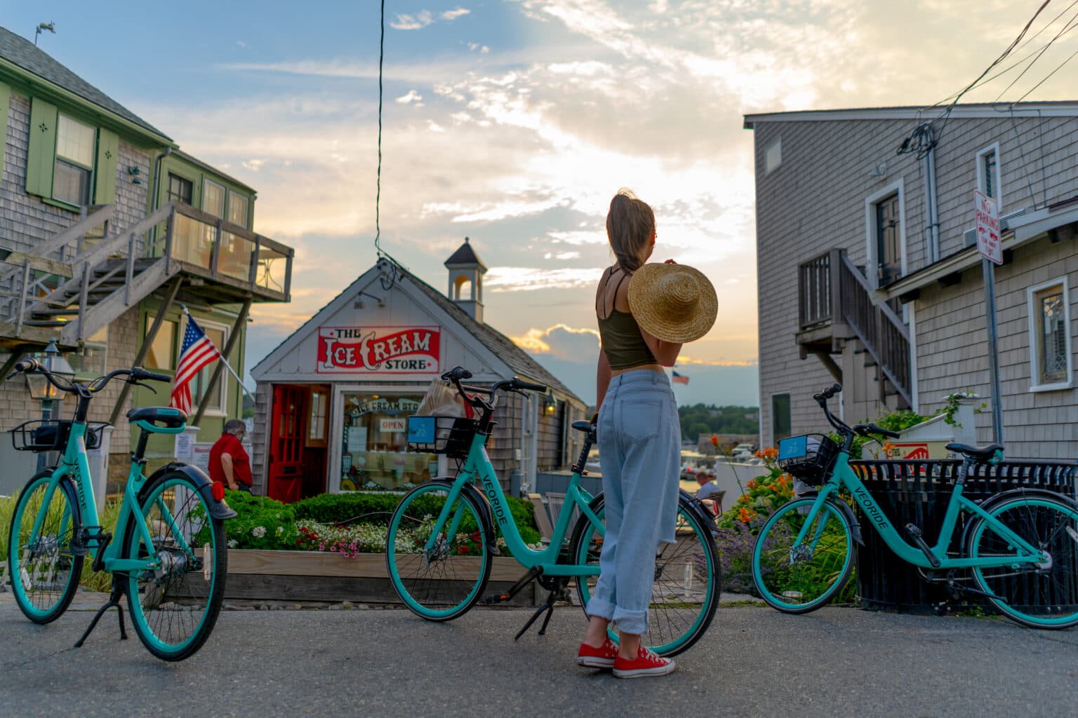 A summer evening on Bearskin Neck: teal rental bikes lined up outside The Ice Cream Store at golden hour